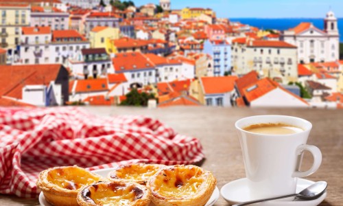 cup of coffee and plate of traditional portuguese pastries - Pastel de nata, over Alfama district, lisbon, Portugal.